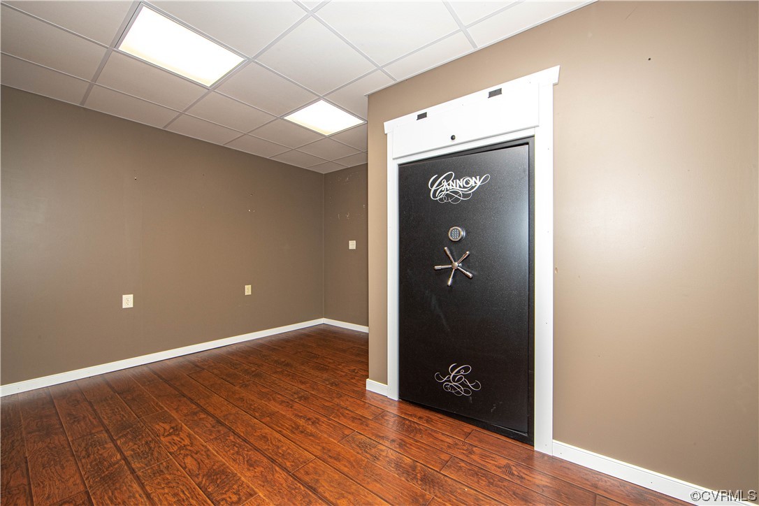 Empty room with a large black Cannon safe, taupe walls, and reddish-brown flooring.