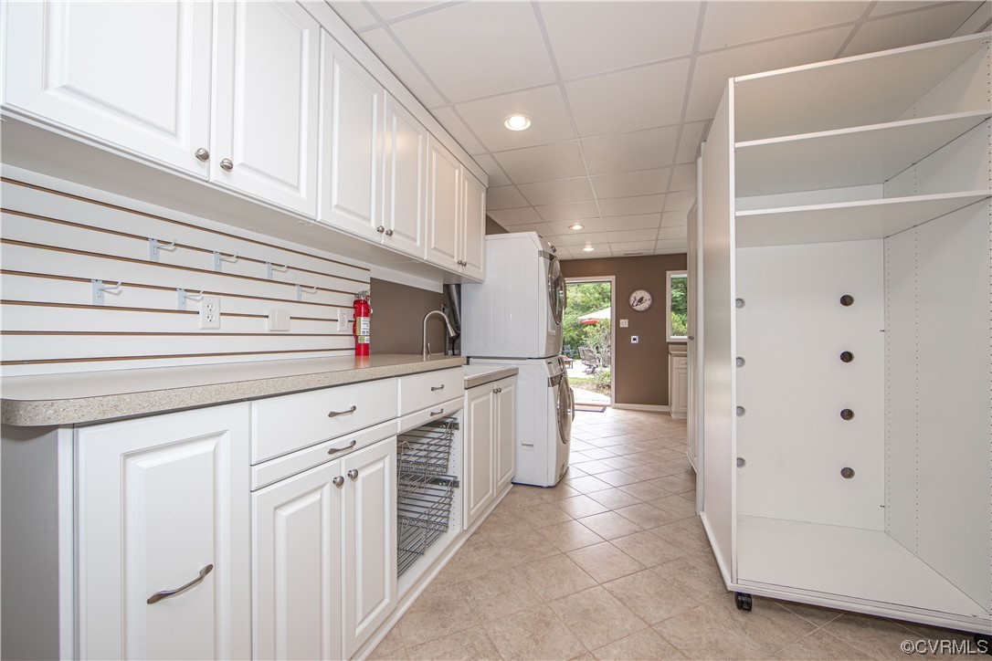 Laundry room with white cabinetry, washer and dryer, utility sink, and open shelving.