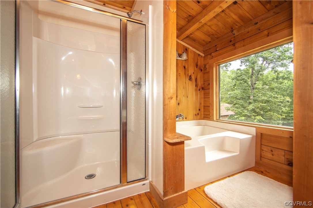 Bathroom with a white shower and soaking tub in a knotty wood alcove beside a large window.