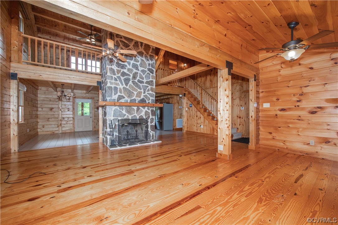 Wood-paneled living room with a large stone fireplace, vaulted ceiling, and open loft.