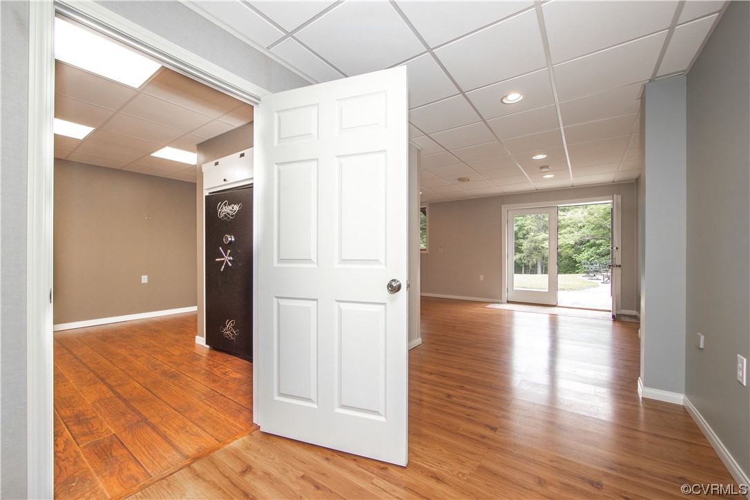 Unfurnished interior with wood-look floors, an open paneled door, and glass doors overlooking trees.