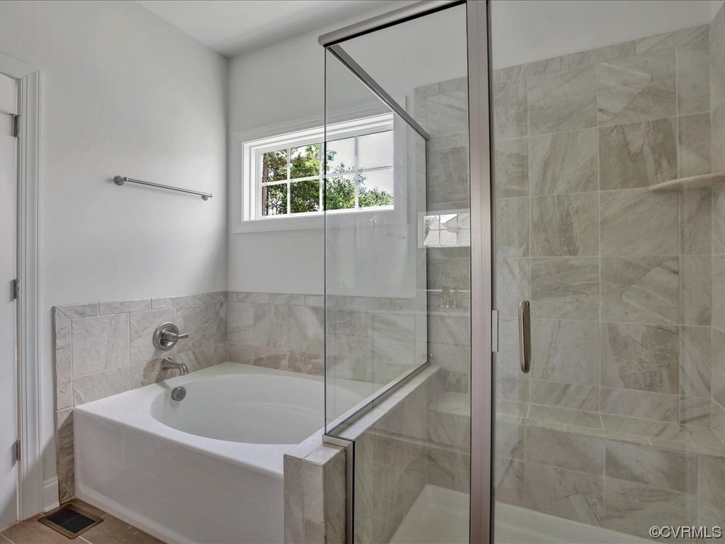 Bathroom with a soaking tub, glass-enclosed tiled shower, and window.