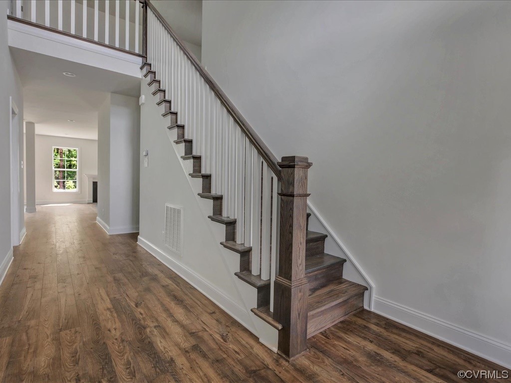 Entry hall with hardwood floors and a dark wood staircase with white balusters.