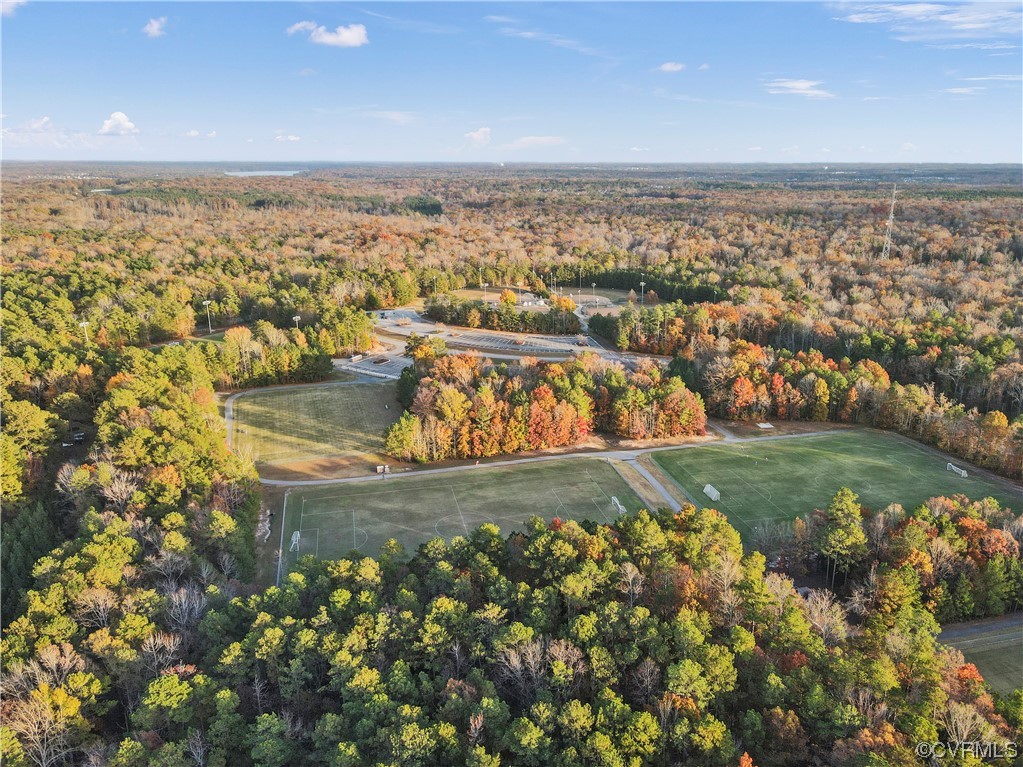 Aerial view of soccer fields amid colorful autumn woodland.