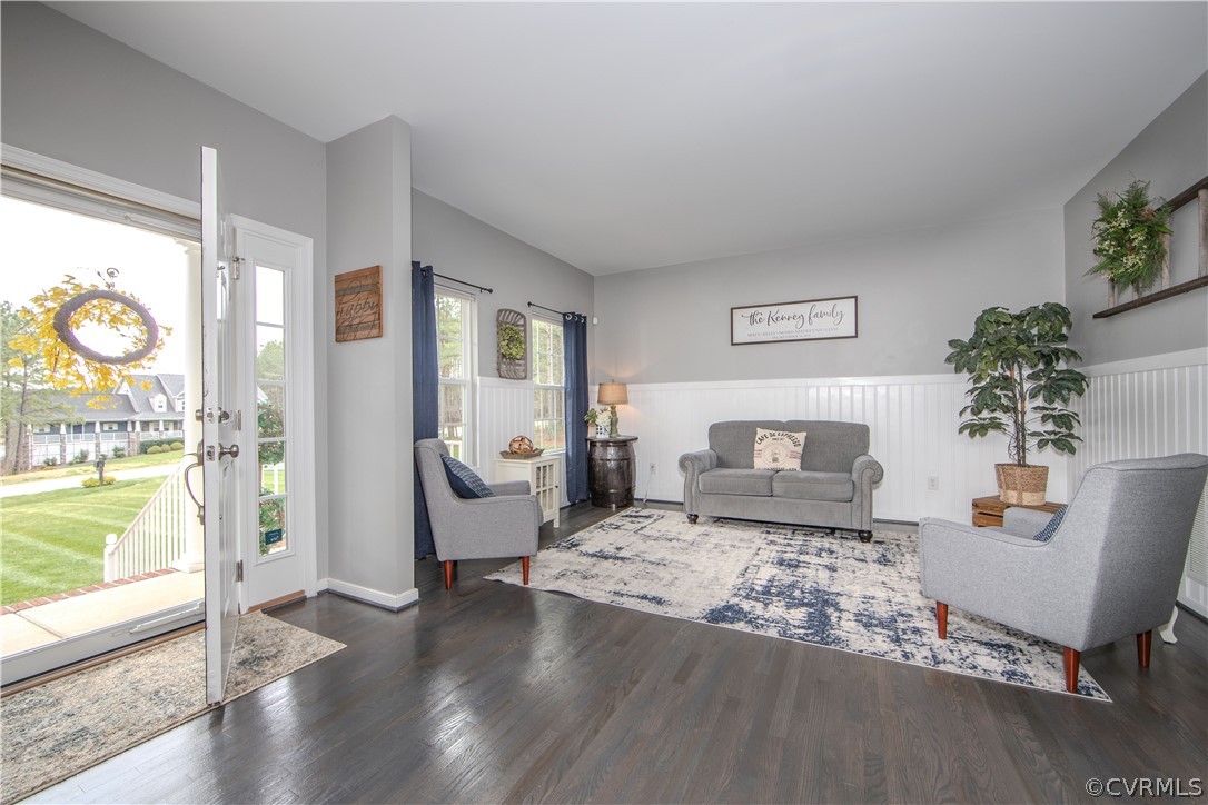 Living room with gray seating, a blue-and-white rug, and an open front door.
