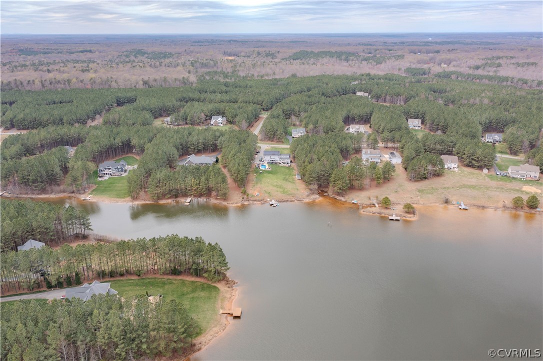 Aerial view of wooded waterfront homes along a broad inlet.