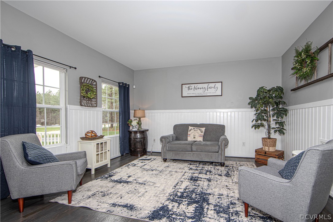 Living room with gray seating, navy curtains, white wainscoting, and a large patterned rug.