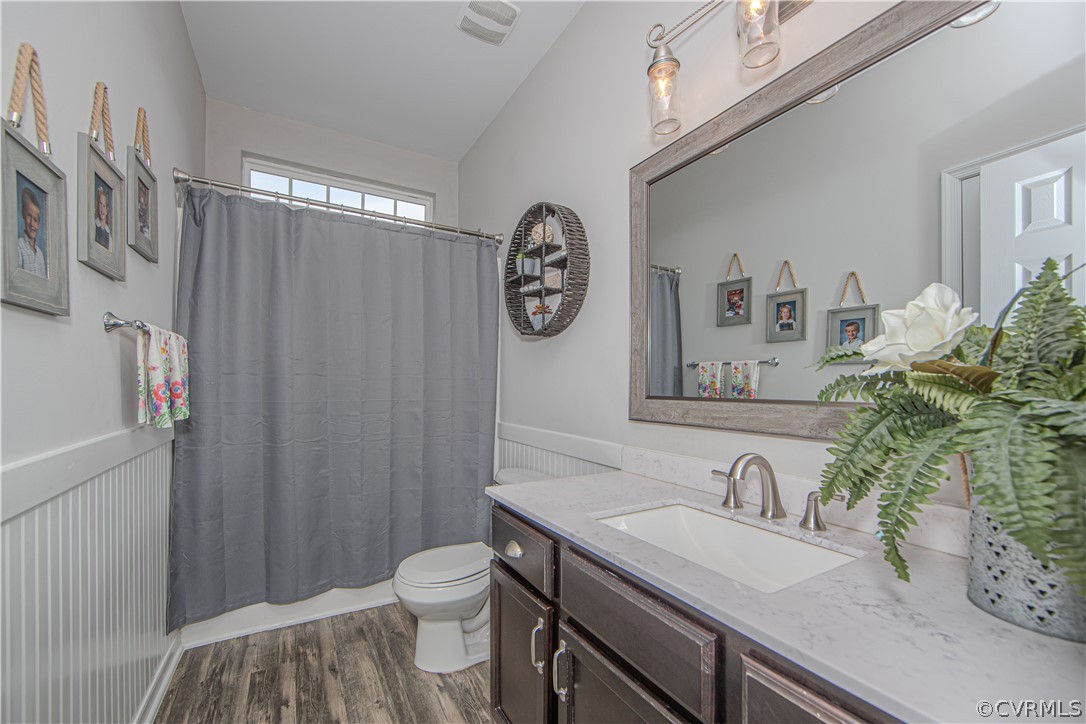 Bathroom with a gray shower curtain, dark wood vanity, marble-look counter, and large framed mirror.