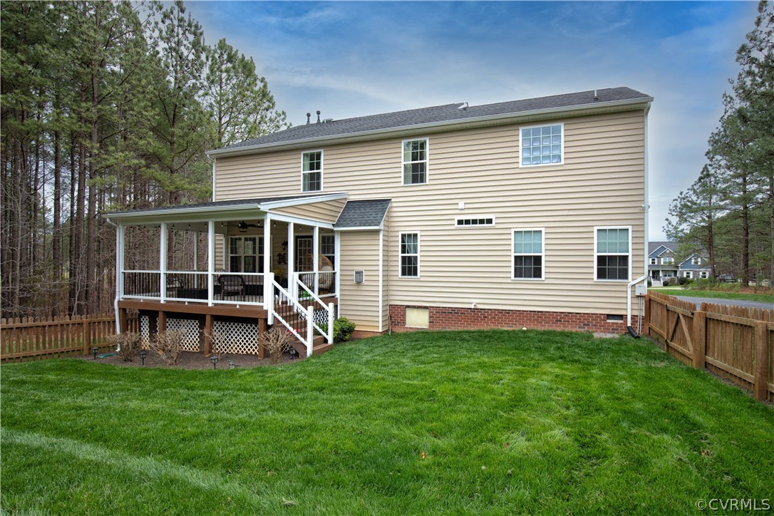 Rear of a beige two-story home with a screened porch and fenced lawn.