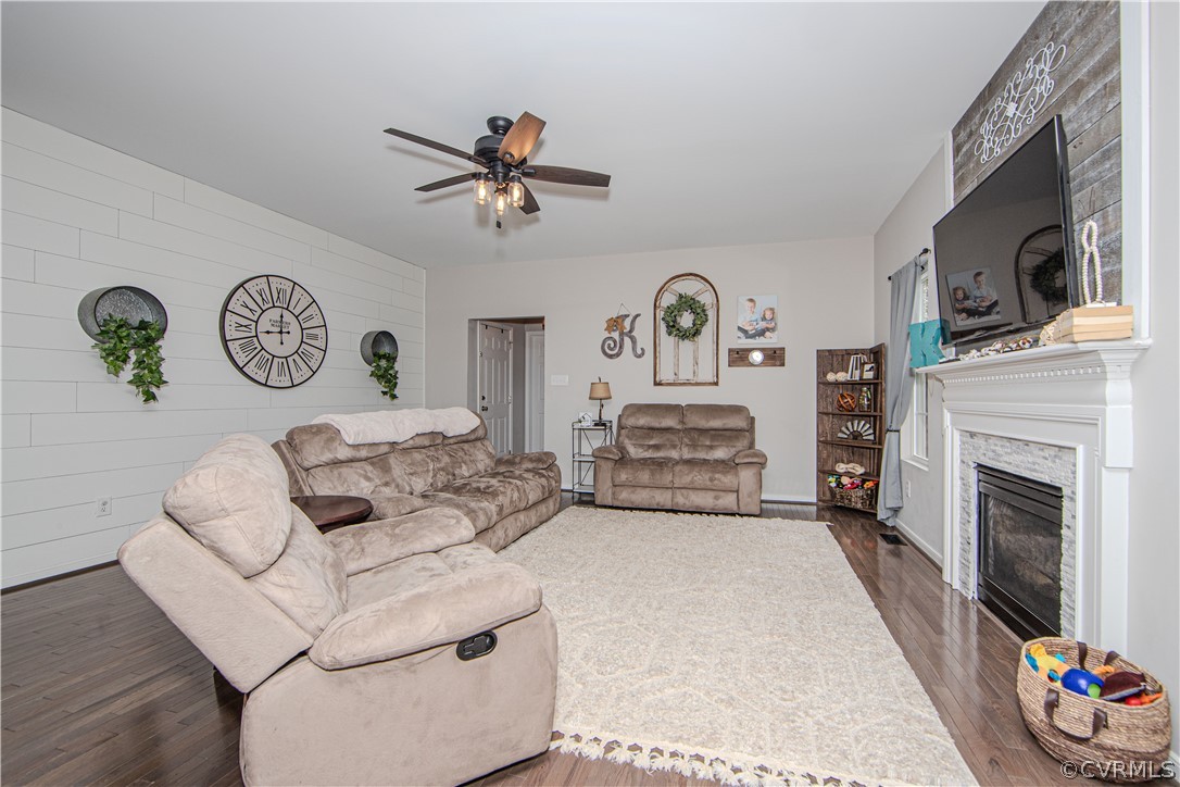 Furnished living room with a large sectional, shiplap accent wall, and fireplace beneath a mounted television.