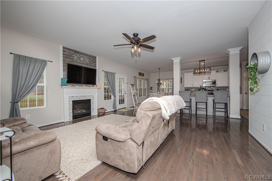 Open-plan living room with a white fireplace, neutral sofas, and kitchen island with bar stools.
