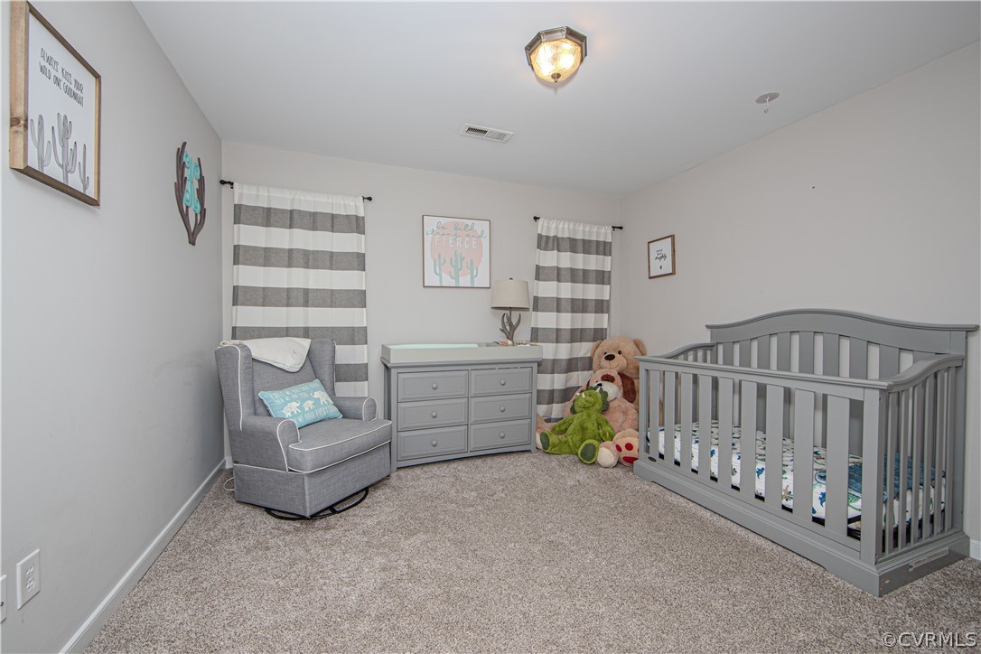Nursery with gray crib, glider, dresser, striped curtains, and plush toys.