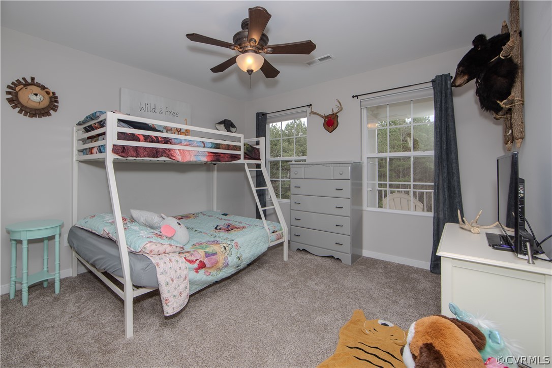 Bedroom with a white bunk bed, colorful bedding, and windows overlooking trees.