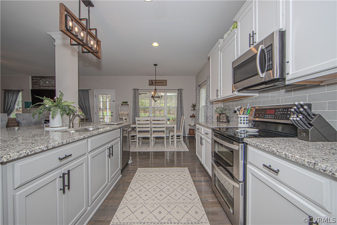Kitchen with white cabinets, granite counters, stainless steel appliances, and a dining area beyond.