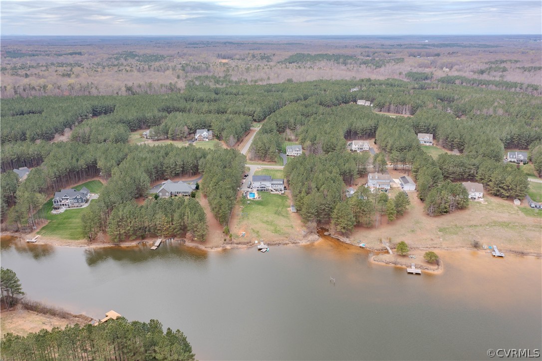 Aerial view of homes along a wooded lakeshore, with private docks and a broad expanse of water.