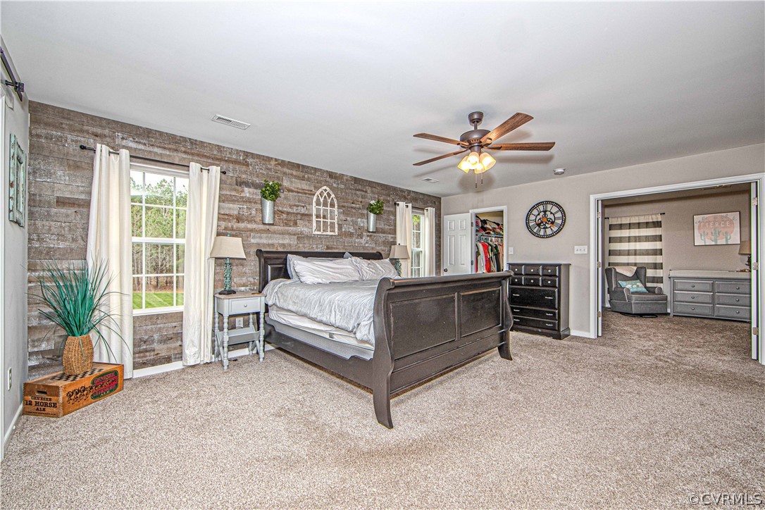 Primary bedroom with a dark wooden bed, rustic plank accent wall, and adjoining sitting area.