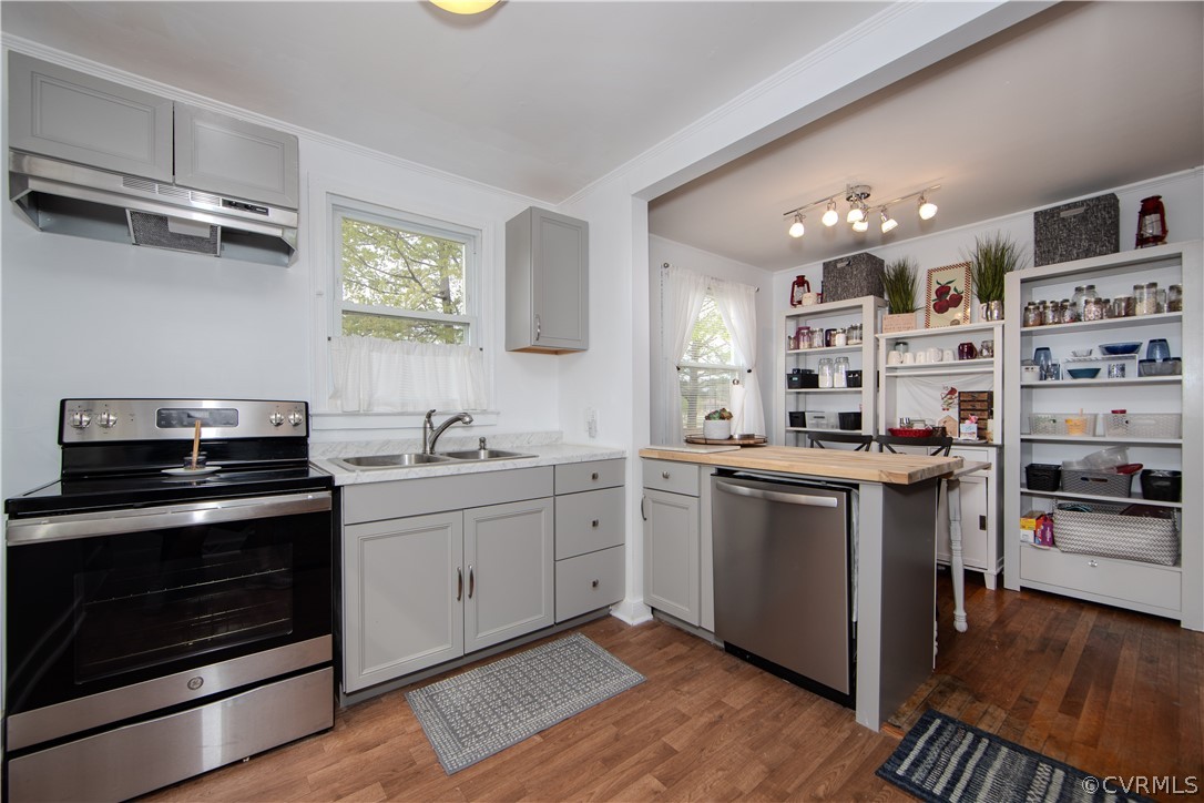 Kitchen with gray cabinets, a butcher-block island, open dish shelves, and hardwood floors.