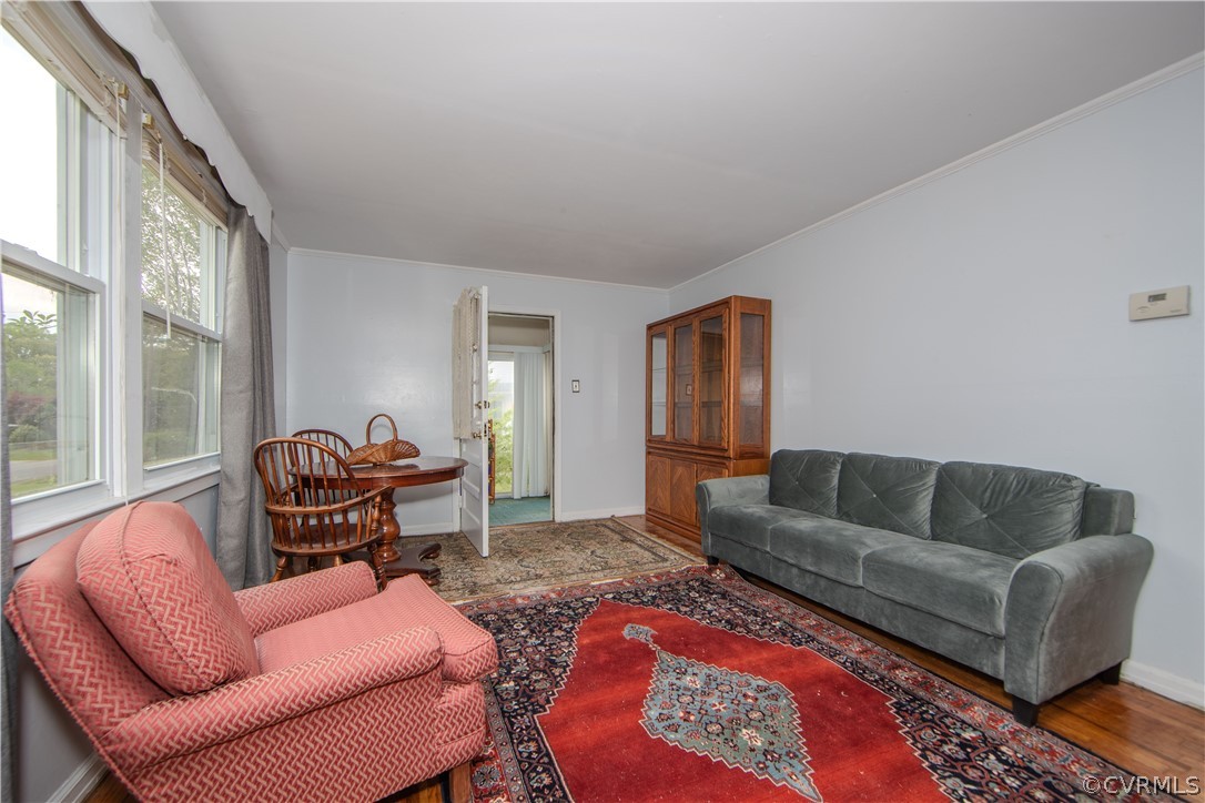 Living room with large windows, gray sofa, coral armchair, and red patterned rug.
