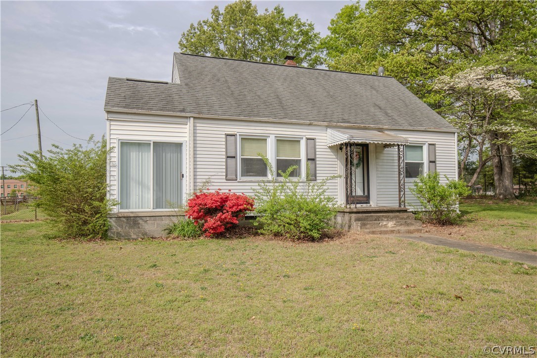 Single-story home with a covered porch, sliding glass doors, and a red flowering shrub.
