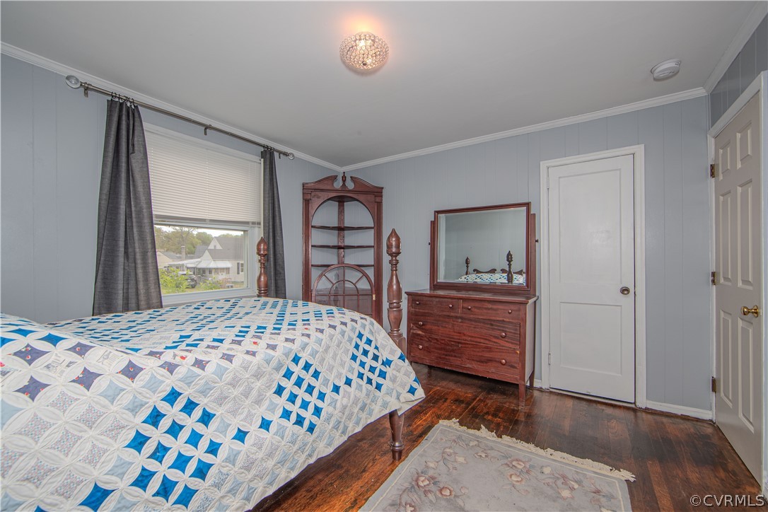 Bedroom with a blue-and-white quilt, dark wood furniture, and hardwood floors.