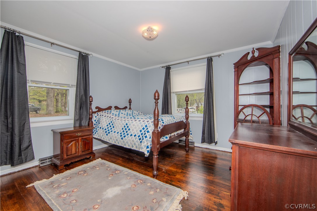 Bedroom with a carved wooden bed, blue-and-white quilt, dark hardwood floors, and matching furniture.