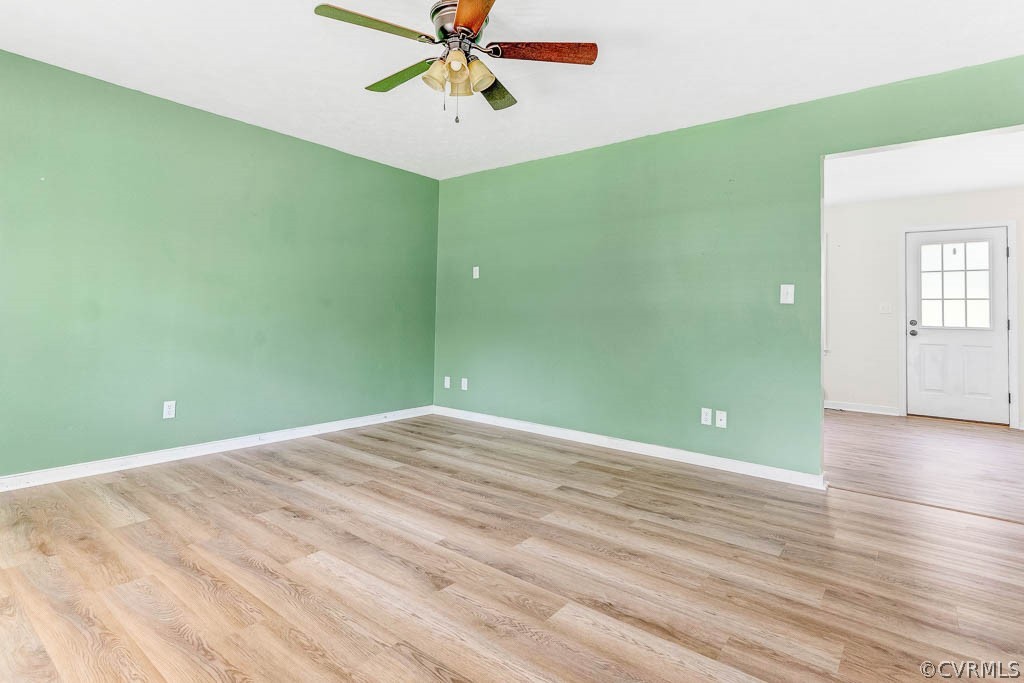 Vacant living room with mint-green walls, wood-look flooring, and a ceiling fan.