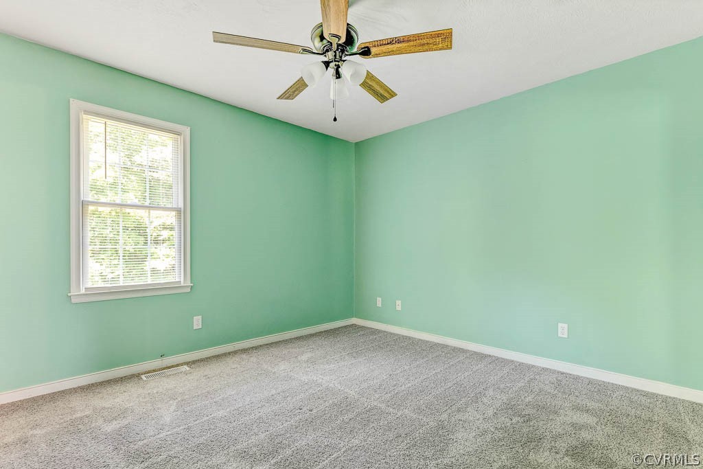 Empty bedroom with mint-green walls, gray carpet, and a wood-blade ceiling fan.