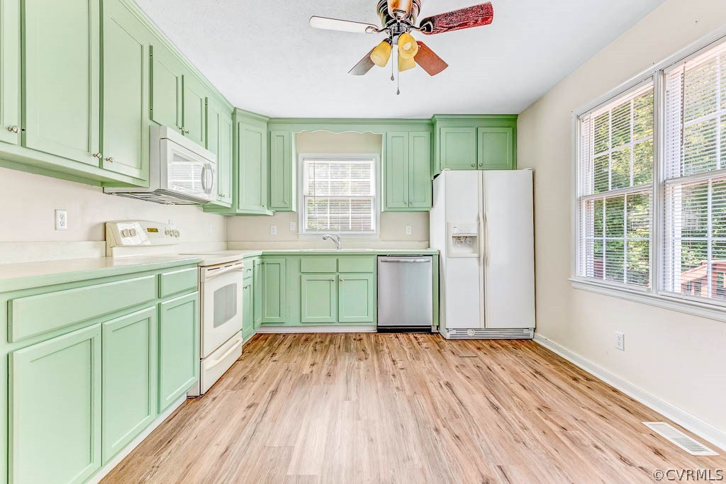Kitchen with mint-green cabinets, wood-look flooring, and large windows.