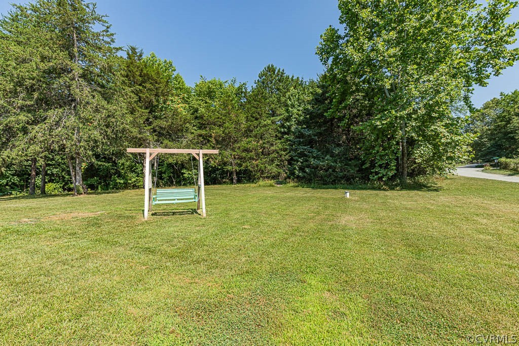 Mowed lawn with a green bench swing beside a wooded lot.