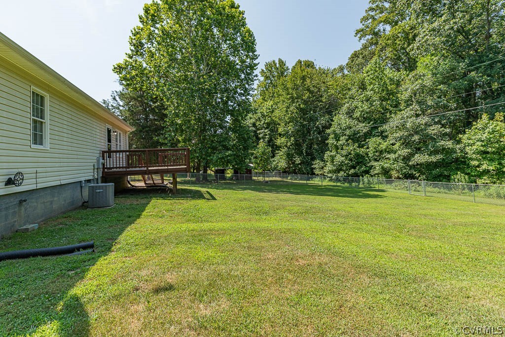 House beside a broad grassy yard, with a raised deck and mature trees.