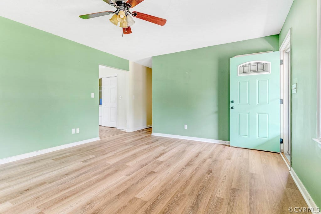 Vacant entry room with mint-green walls, turquoise front door, and light wood-look flooring.