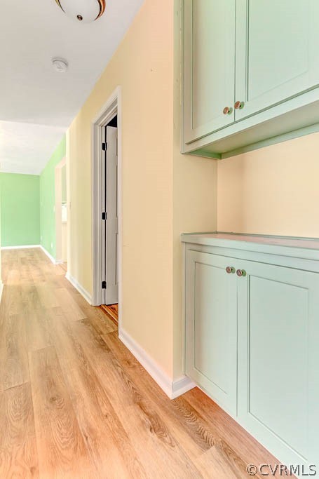 Hallway with pale green built-in cabinets and light wood-look flooring.