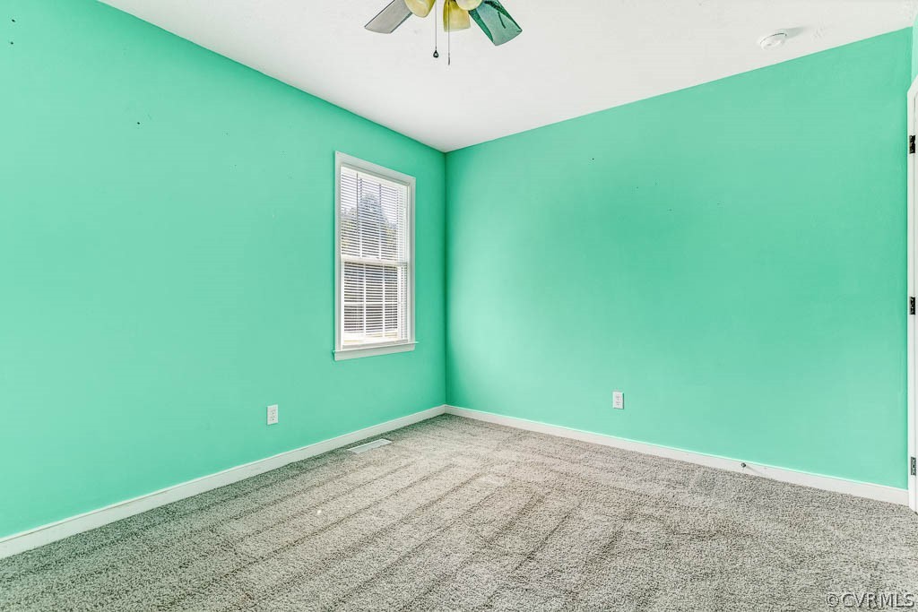 Empty bedroom with turquoise walls, gray carpet, and a window with blinds.