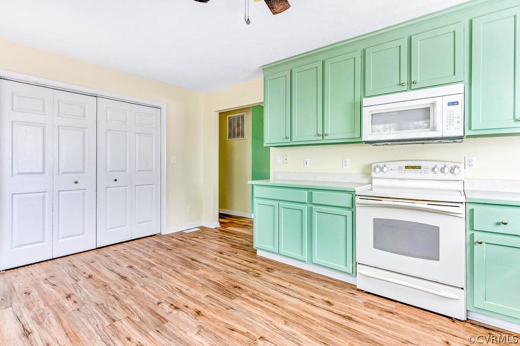 Unfurnished kitchen with mint-green cabinets, white appliances, and wood-look flooring.