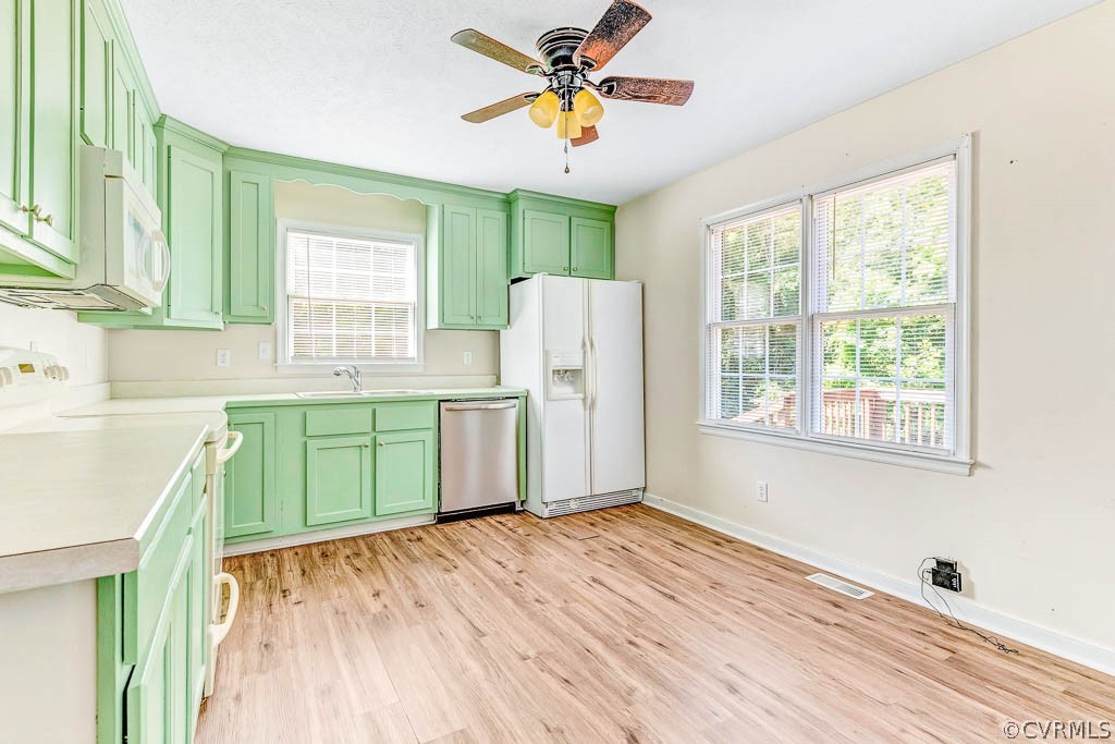 Kitchen with mint-green cabinets, white appliances, and large windows.
