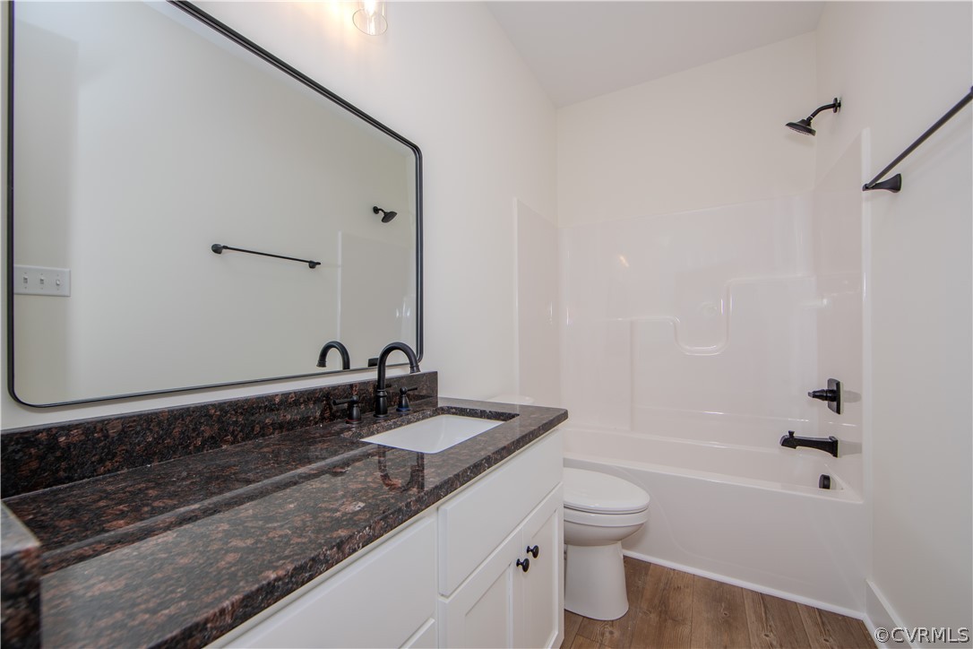 Bathroom with a dark granite vanity, large mirror, and white tub-shower.