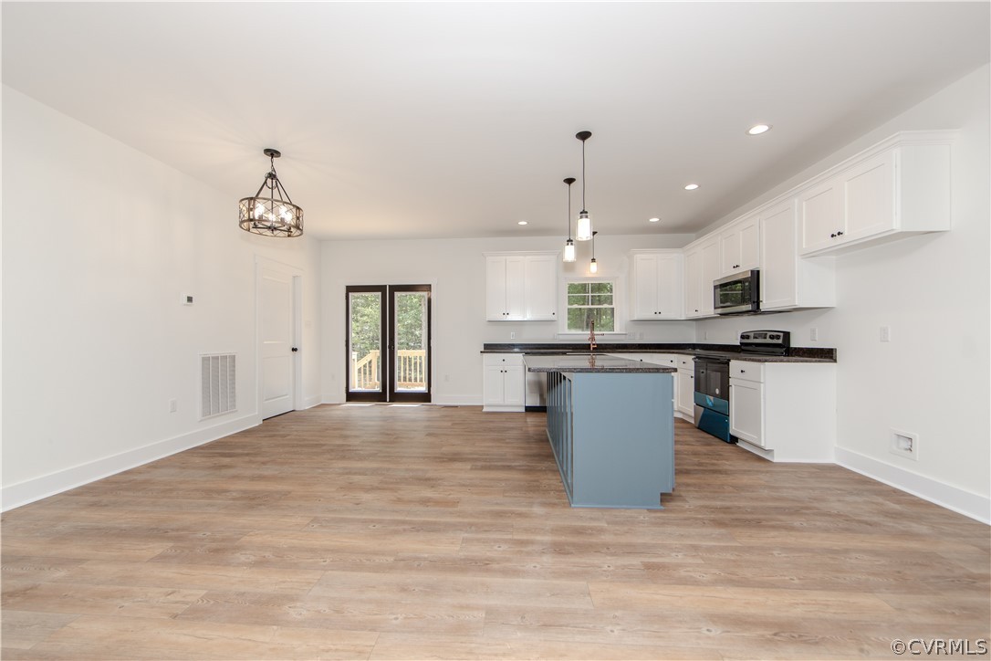 Unfurnished kitchen with a blue-gray island, white cabinetry, and glass doors to a deck.