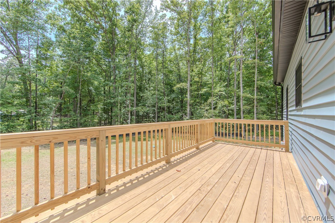 Wooden deck beside a white-sided house, overlooking a wooded backyard.