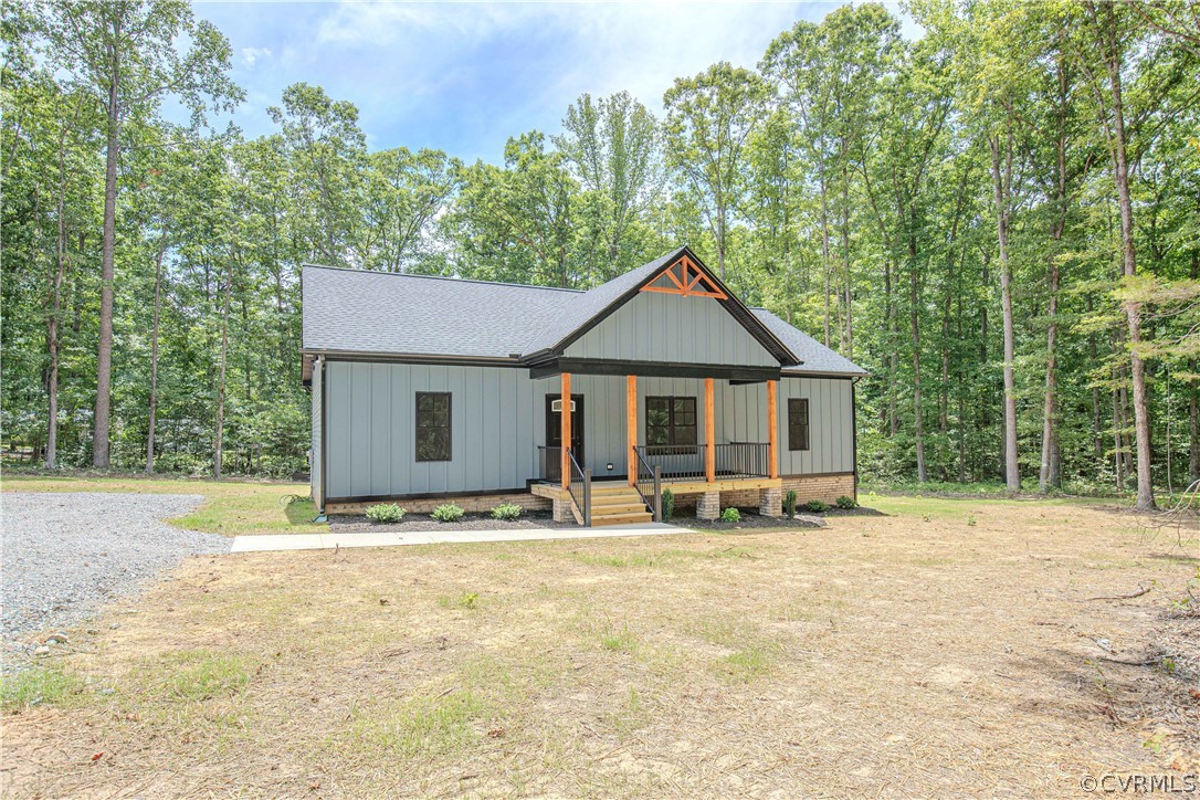 Gray home with a covered porch and orange timber accents, surrounded by leafy trees.