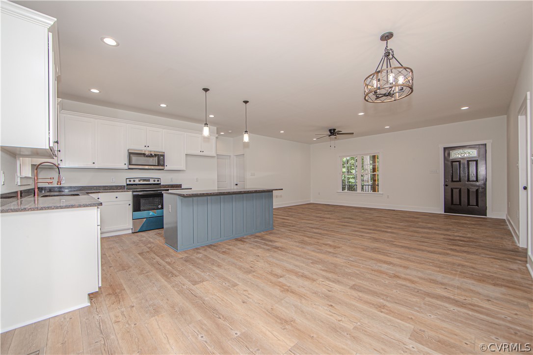 Open-plan kitchen and living area with a blue island, white cabinets, and wood-look flooring.