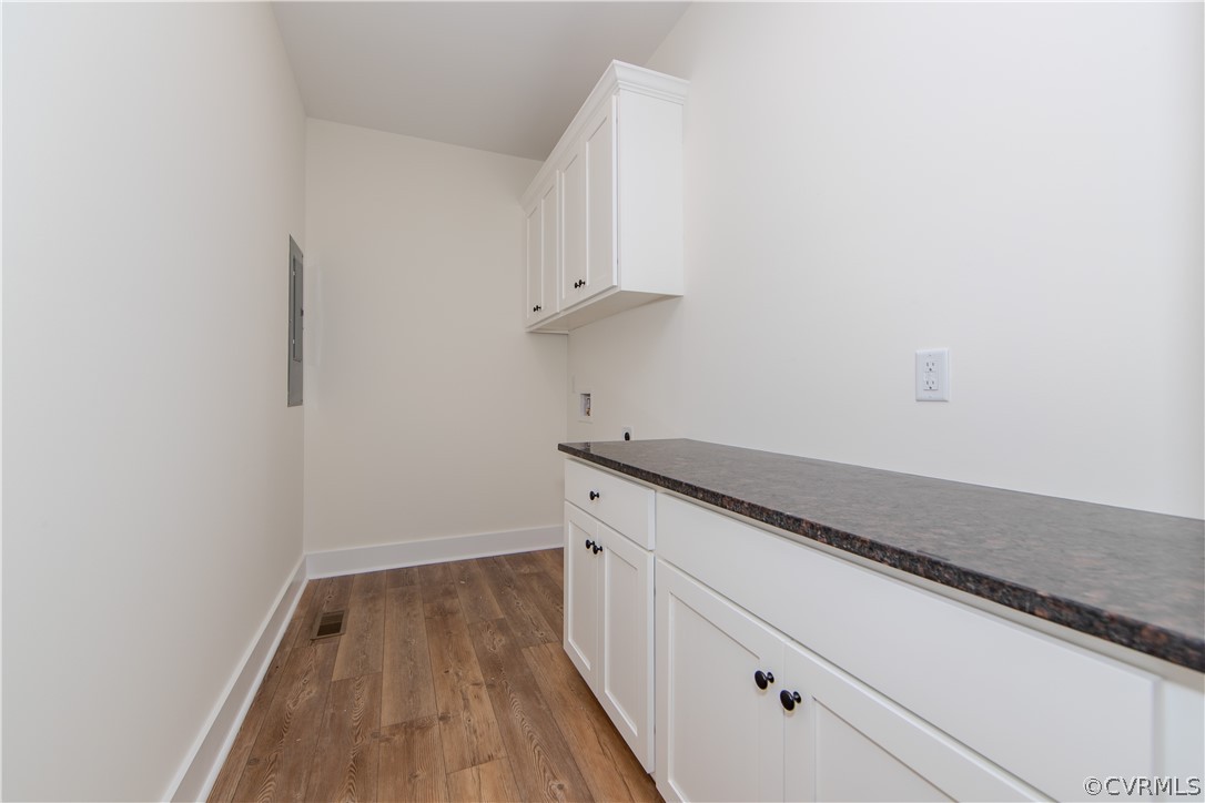 Unfurnished utility room with white cabinetry, a dark countertop, and wood-look flooring.