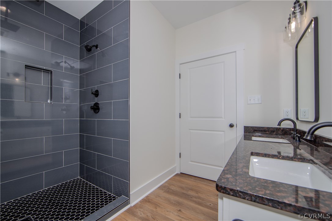 Bathroom with a dark tiled walk-in shower and a stone vanity with a white sink.