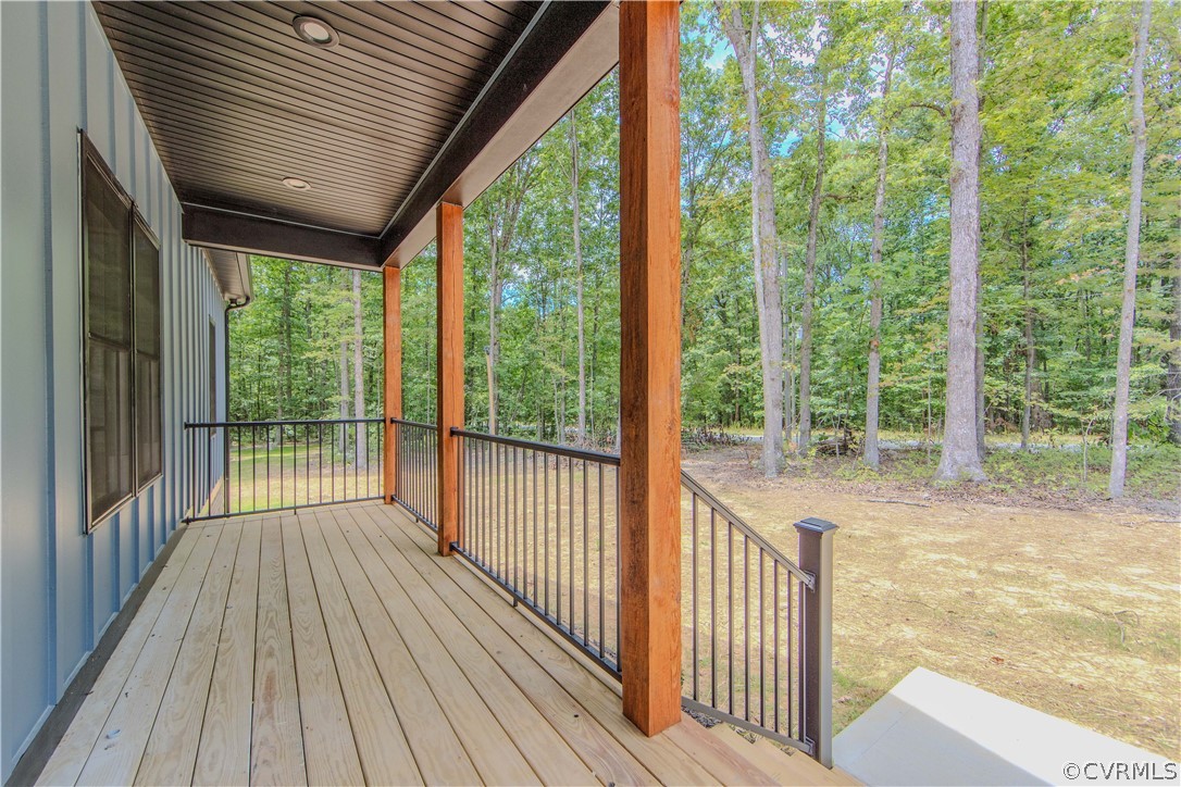 Covered wood deck overlooking a wooded yard, with stained timber posts and black railings.
