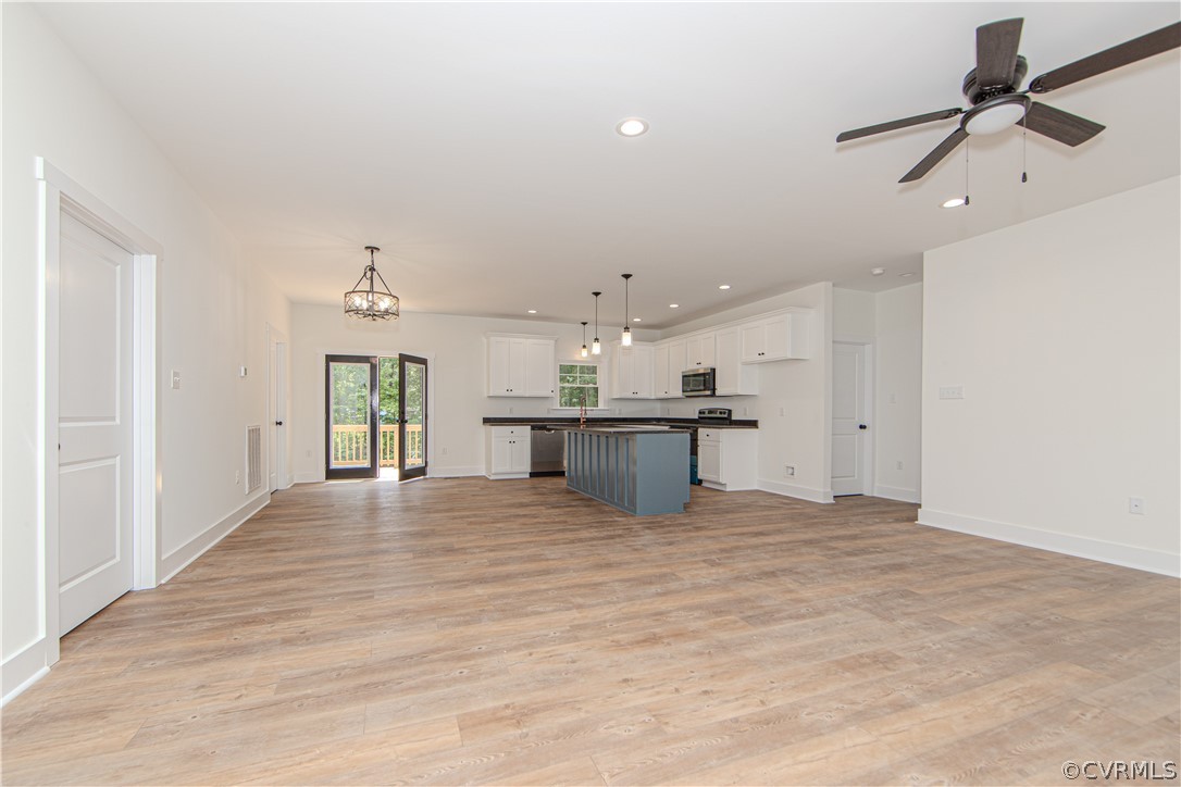 Open-plan kitchen and living area with a blue-gray island, white cabinetry, and glass doors to a deck.