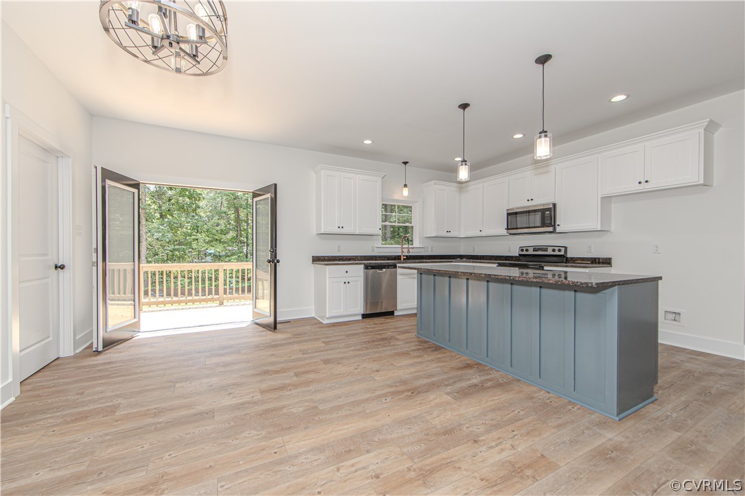 Unfurnished kitchen with a large blue-gray island and open doors to a tree-lined deck.