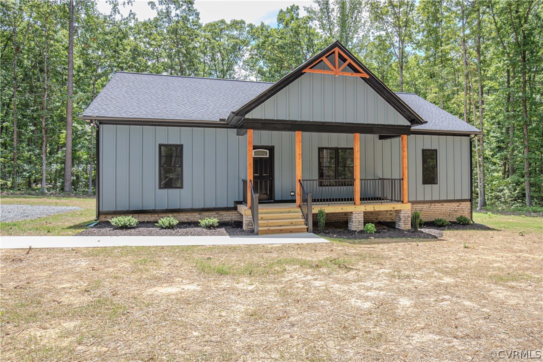 Gray-sided home with a timber-accented covered porch, set among trees.