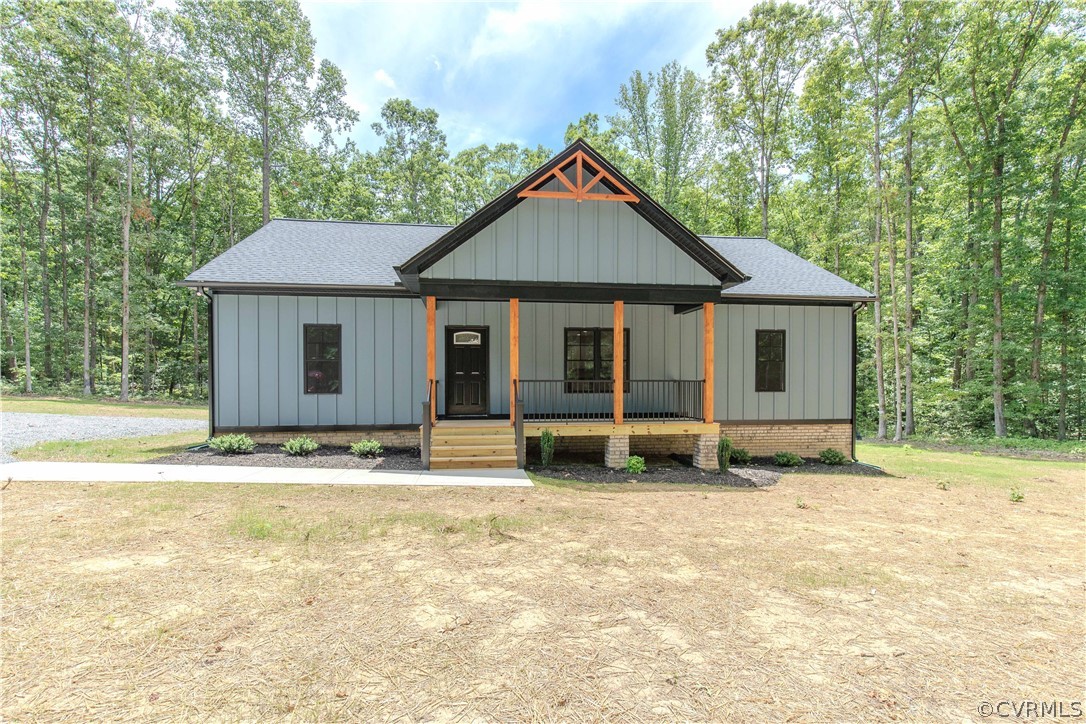Gray house with a timber-trimmed gabled porch, surrounded by mature trees.