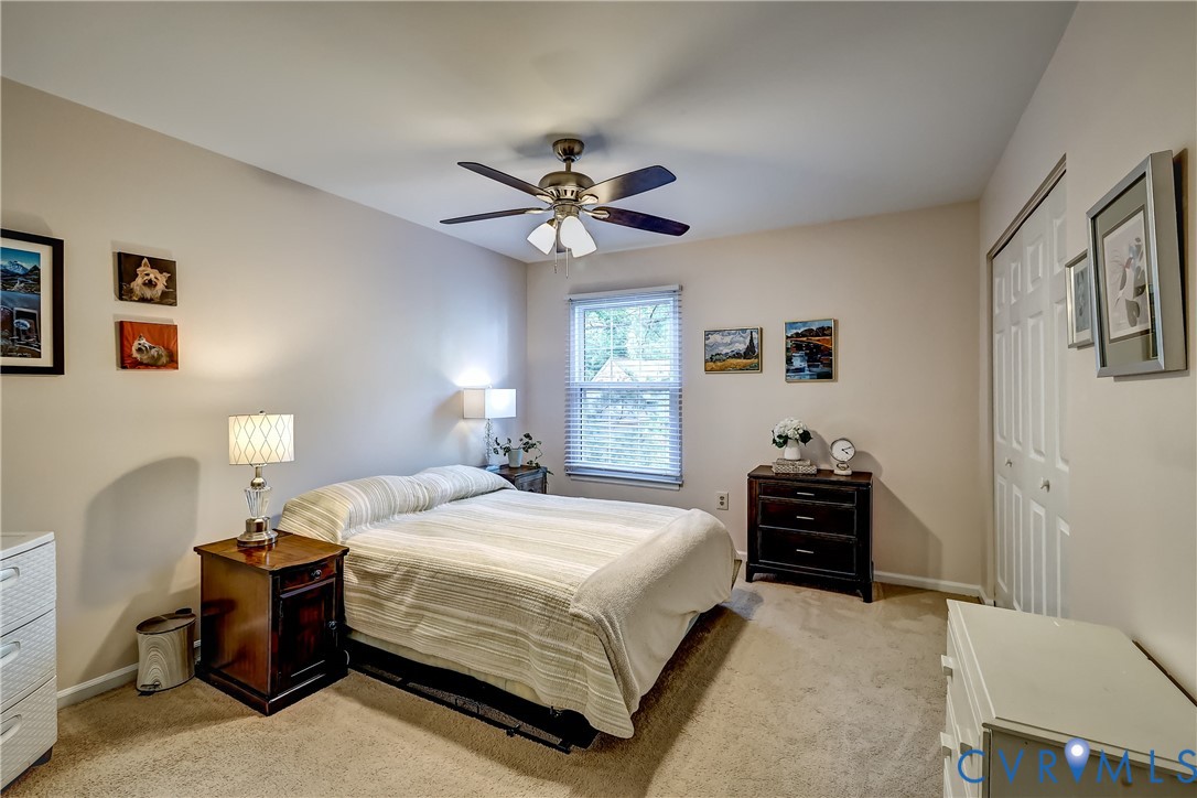 Furnished bedroom with a cream striped bedspread, dark wood nightstands, and a ceiling fan.