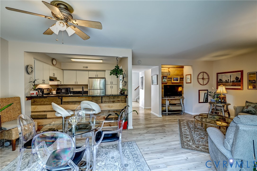 Open-plan living room with a rustic kitchen island, glass dining table, and patterned rugs.