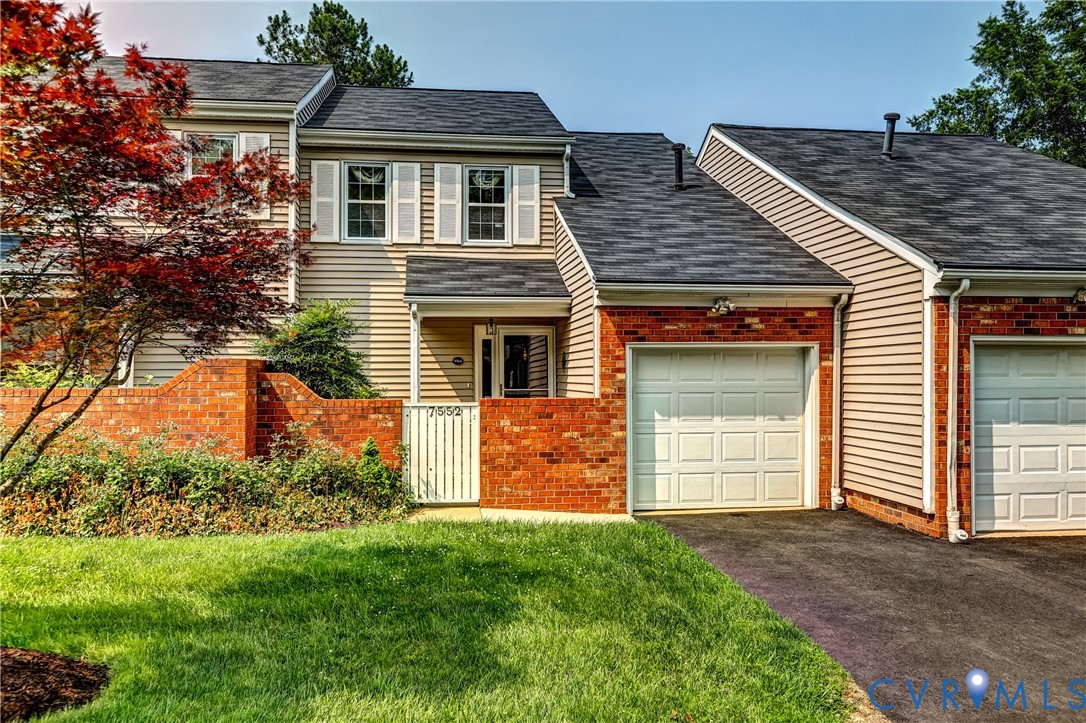 Two-story home with brick accents, an attached garage, and a brick-fronted entry gate.